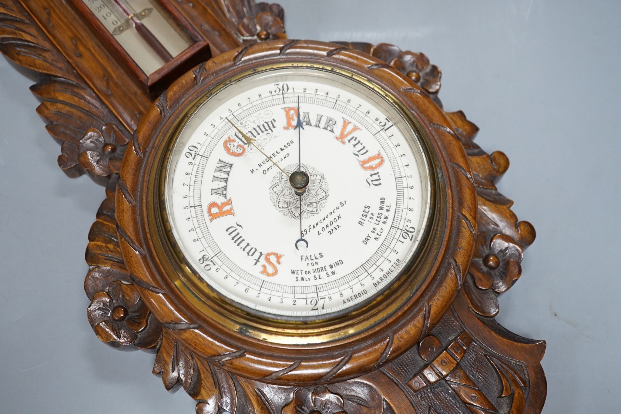 A Victorian carved walnut aneroid barometer with timepiece